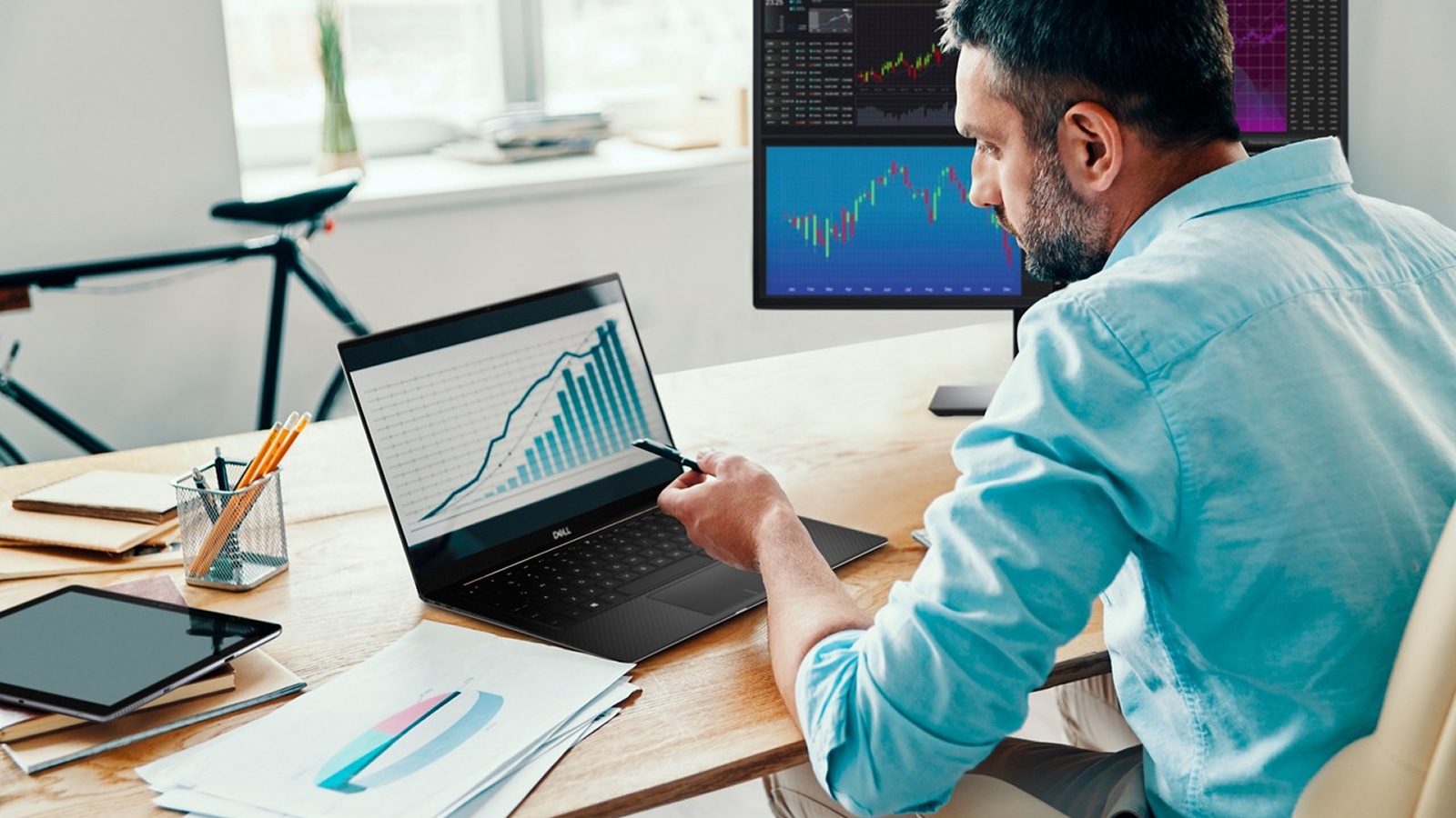 Man at home office desk viewing graphs on a laptop