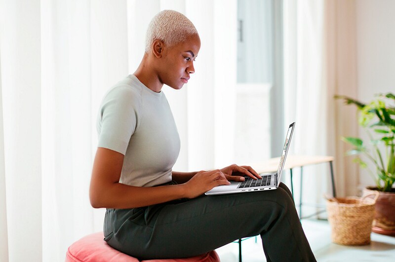 Woman working from a bright room, red cushion stool.