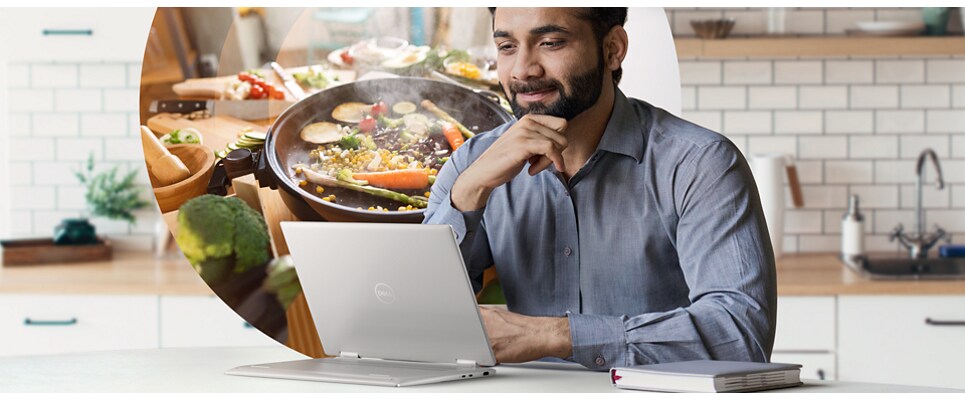 Man in a kitchen using a Dell Inspiron 14 7430 2-in-1 Laptop leaning against a table. 