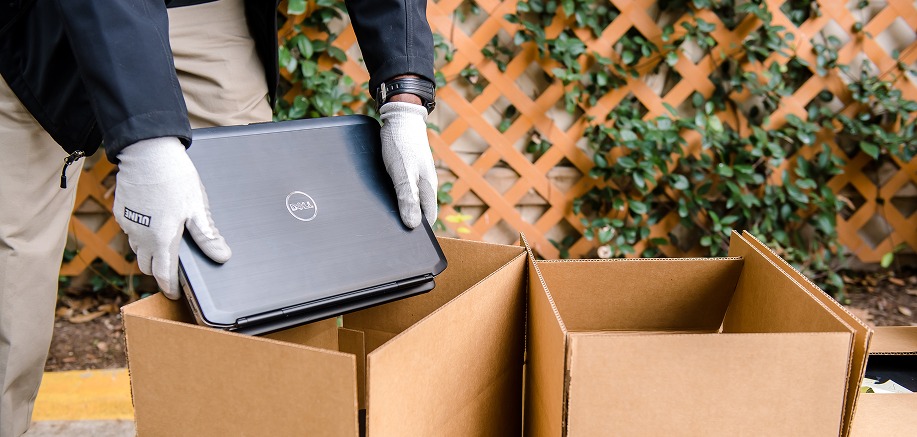 A Dell laptop being placed in a box to send in for recycling.