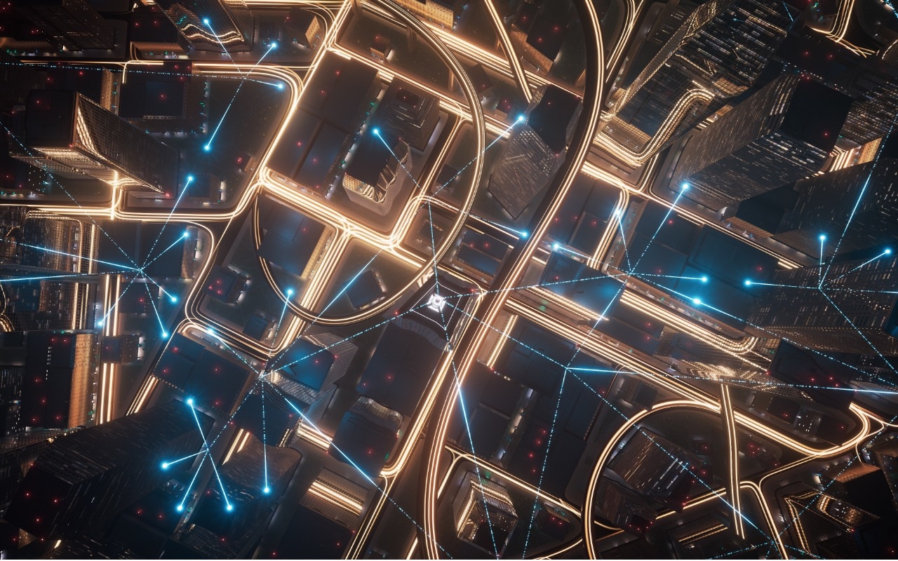 Aerial view of cityscape's buildings and roadways at night, connected by 5G, edge and smart technology.