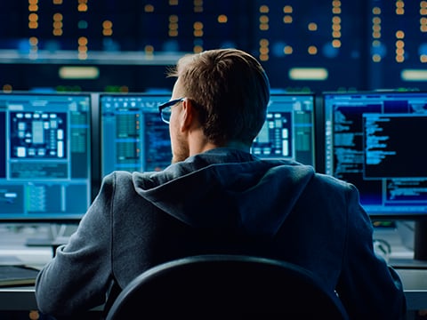 IT Specialist Working on Personal Computer with Monitors Showing Coding Language Program. Technical Room of Data Center with Server Rack.