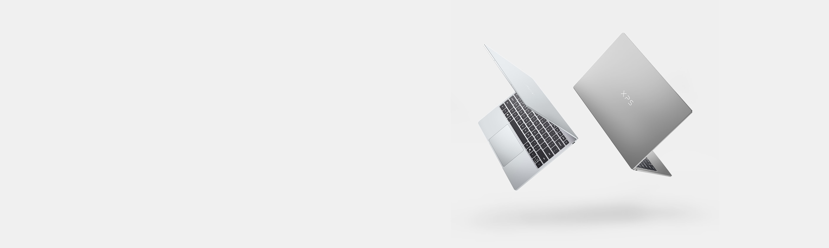 Two floating silver Dell XPS 13 laptops angled to show the keyboard and outer lid against a light gray background.