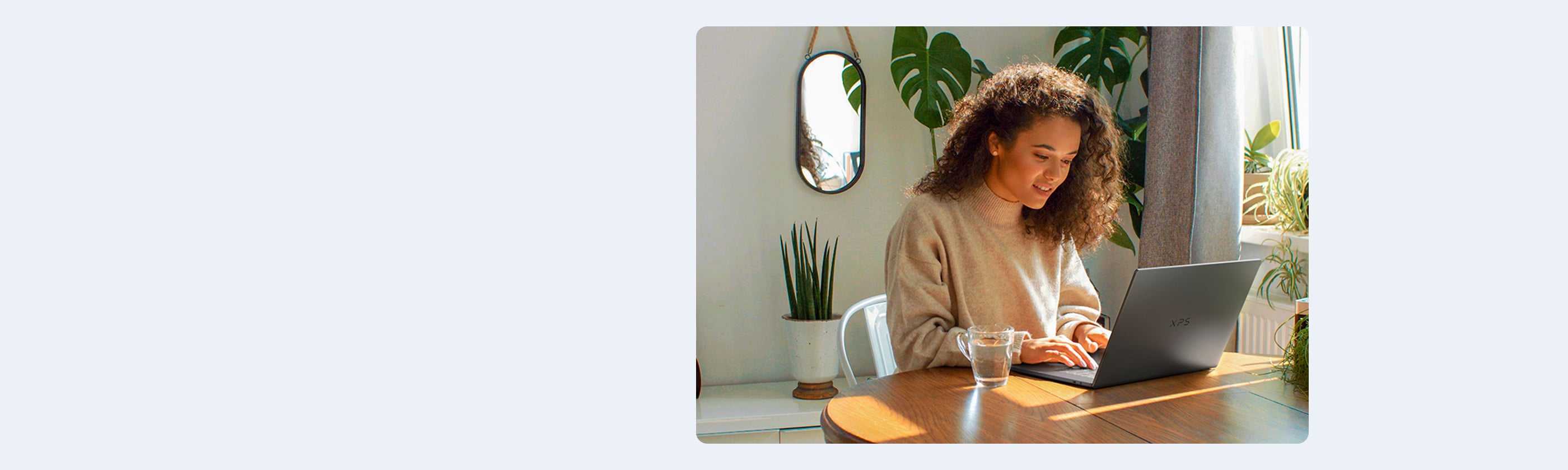 Woman Sitting at her Kitchen Table using the XPS 16 DA16260 Laptop
