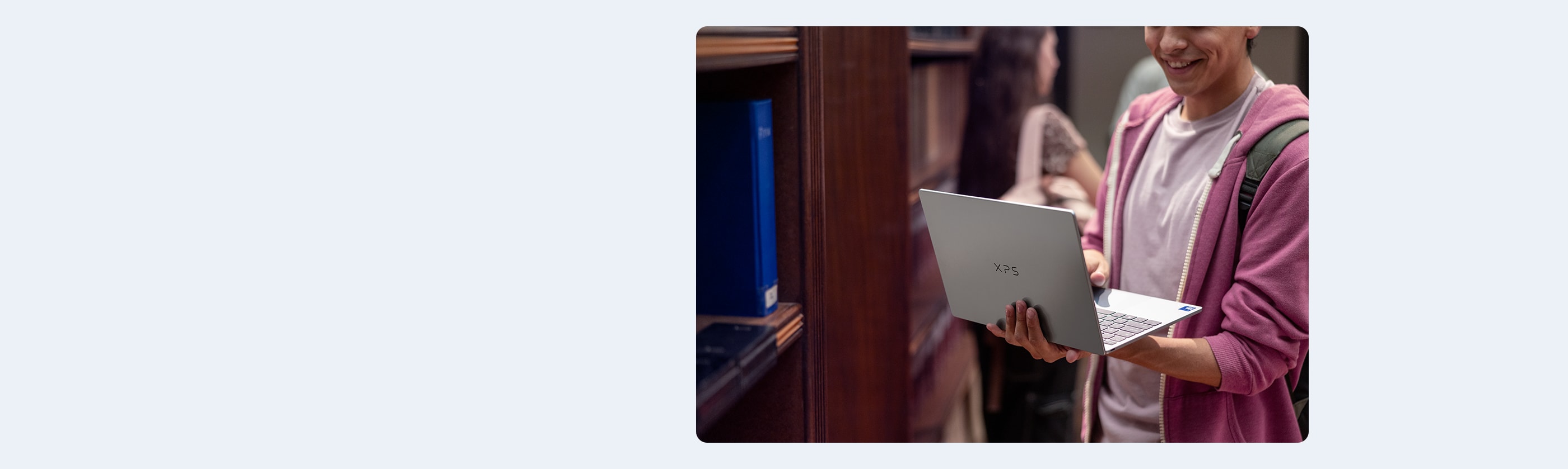 Student Smiling While Holding Laptop in a Library