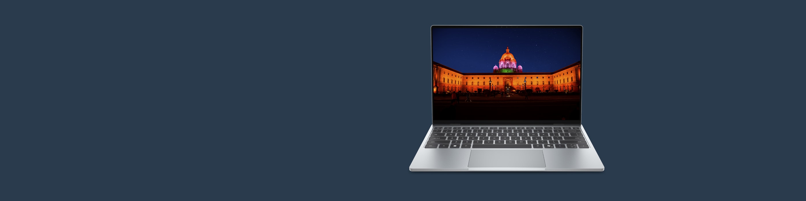 Open laptop on dark blue background showing a colorful illuminated building at night.