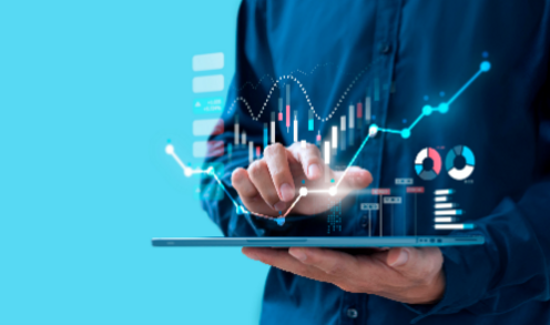 Person holding a tablet displaying glowing floating data charts and graphs against a solid blue background.