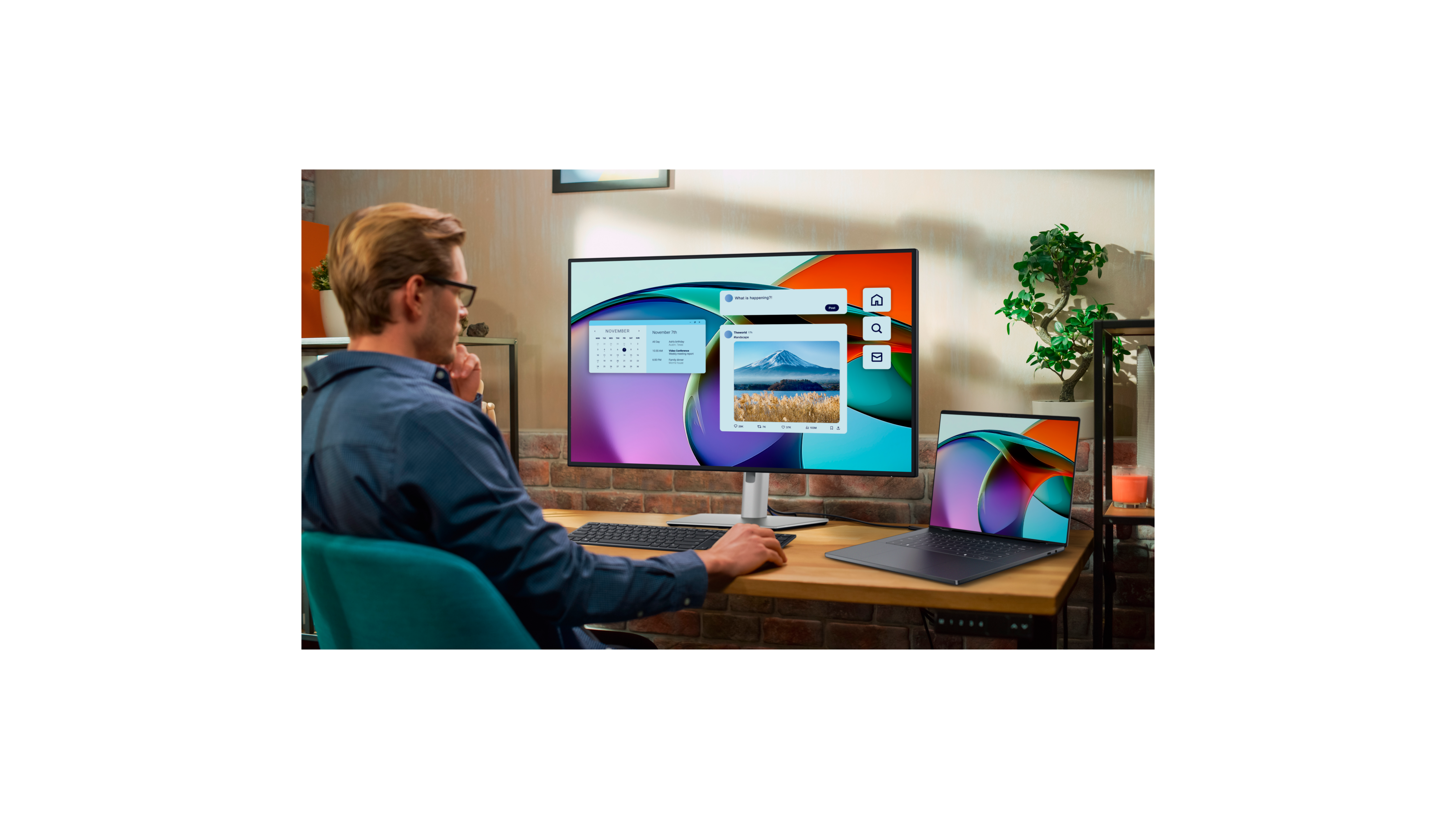 At home office, man using desktop computer, small plant.