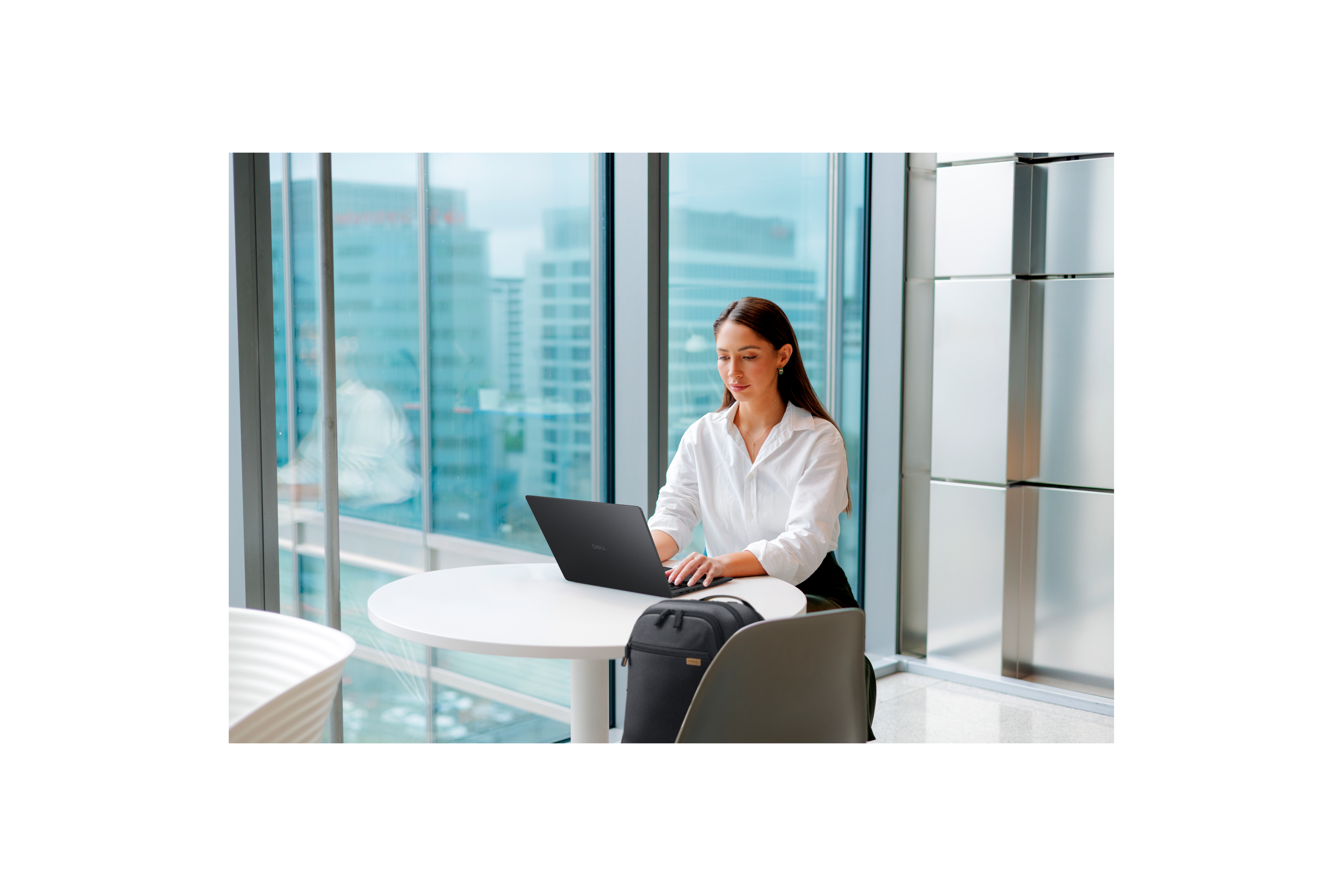Woman sitting at a table working on her Dell laptop.