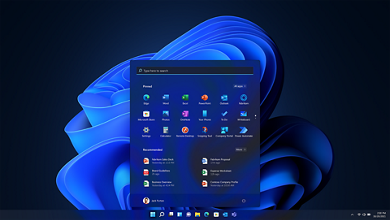 Laptop homepage with Microsoft Windows 11 blue logo as background and search tool opened.