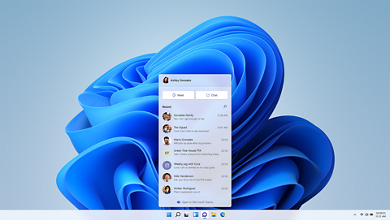 Picture of a laptop homepage with Microsoft Windows 11 blue logo as background and Microsoft Teams opened. 