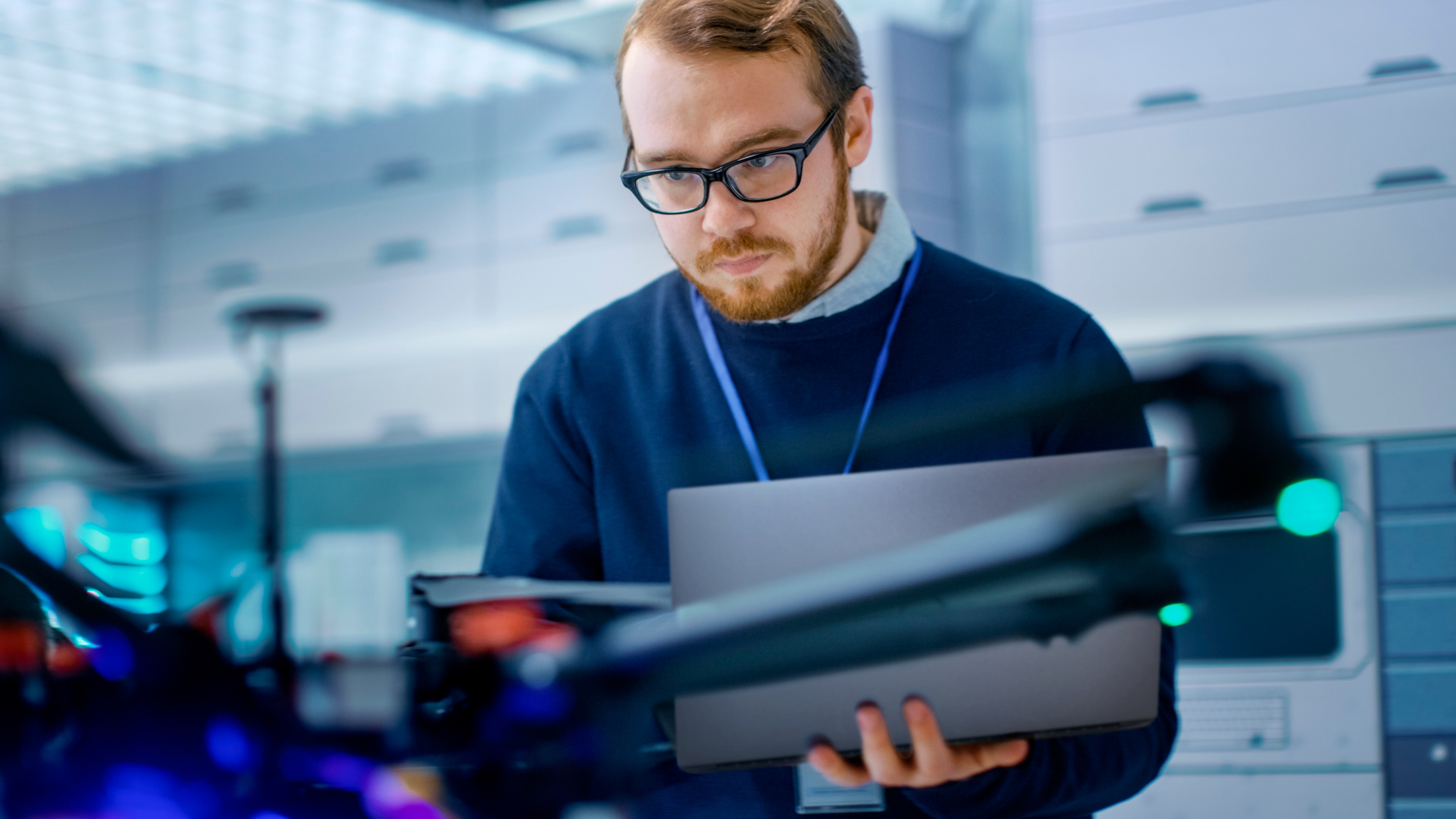 Young Male Engineer Programs Drone while Holding Laptop in His Hands