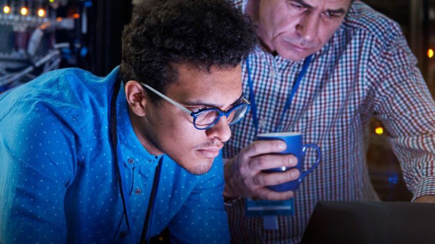 Two Server Room Workers Looking at a Monitor