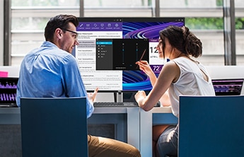 Man and woman talking while sitting in front of Dell products at a table.