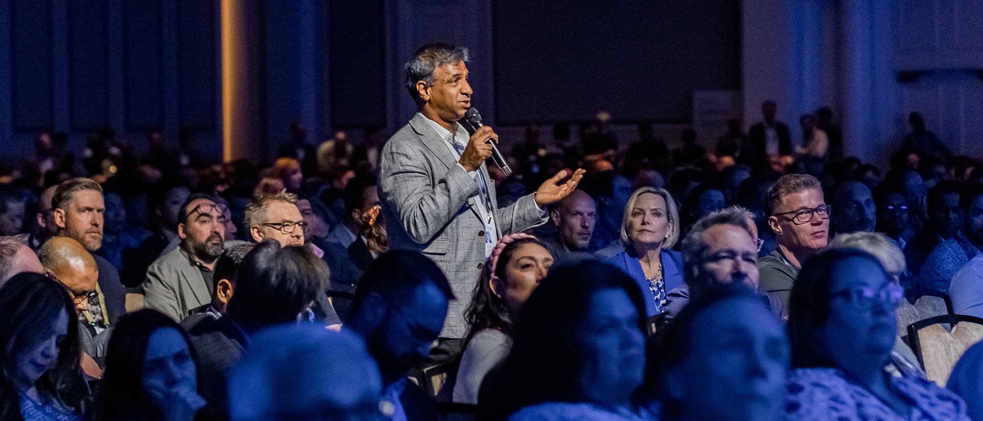Conference attendee standing to ask a question from the crowd