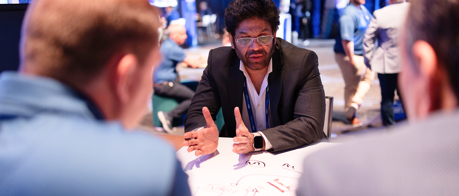Two conference attendees discussing their business with a Dell partner leader in a dedicated space