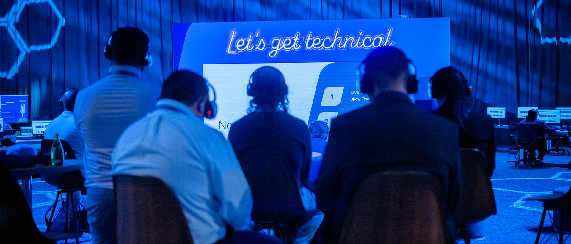 View over shoulders of five conference attendees at a technical sesson