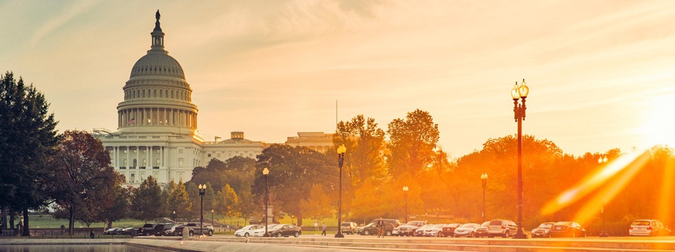 The Capitol building at sunrise reflecting in a nearby pool