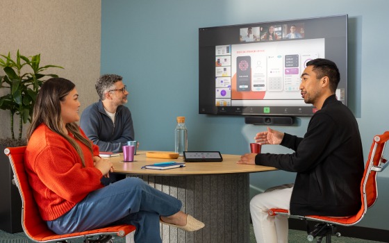 Three people in a room meeting via Zoom with three others using a Logitech MeetUp 2