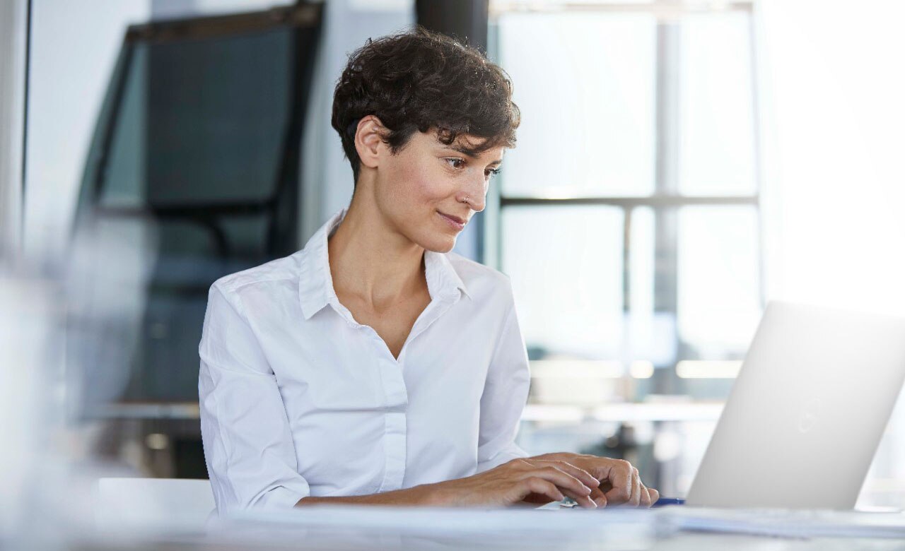 女性商務人士坐在辦公室內的辦公桌前使用筆記型電腦