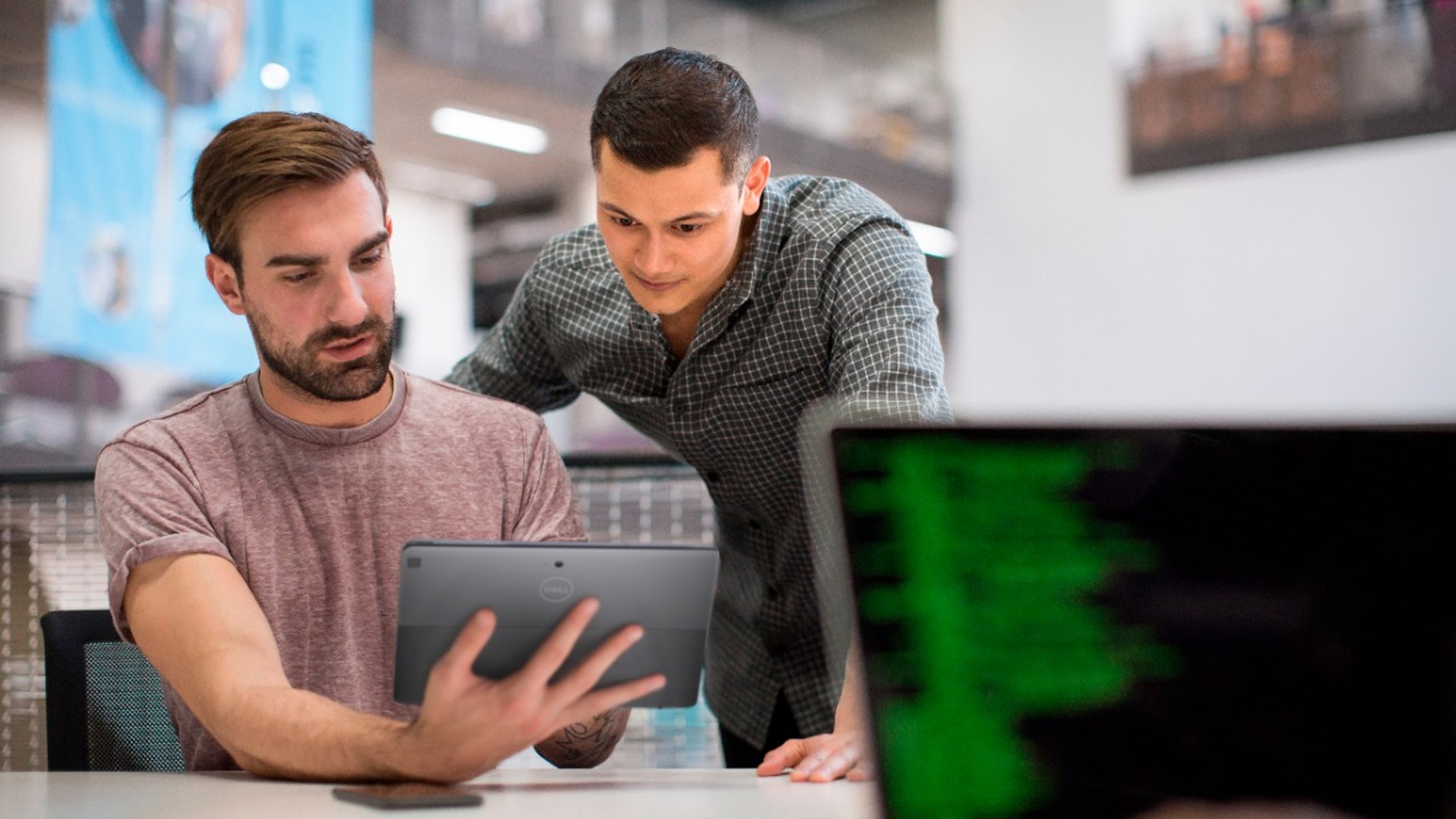 Two men at a standing desk, having a meeting and using a Dell laptop
