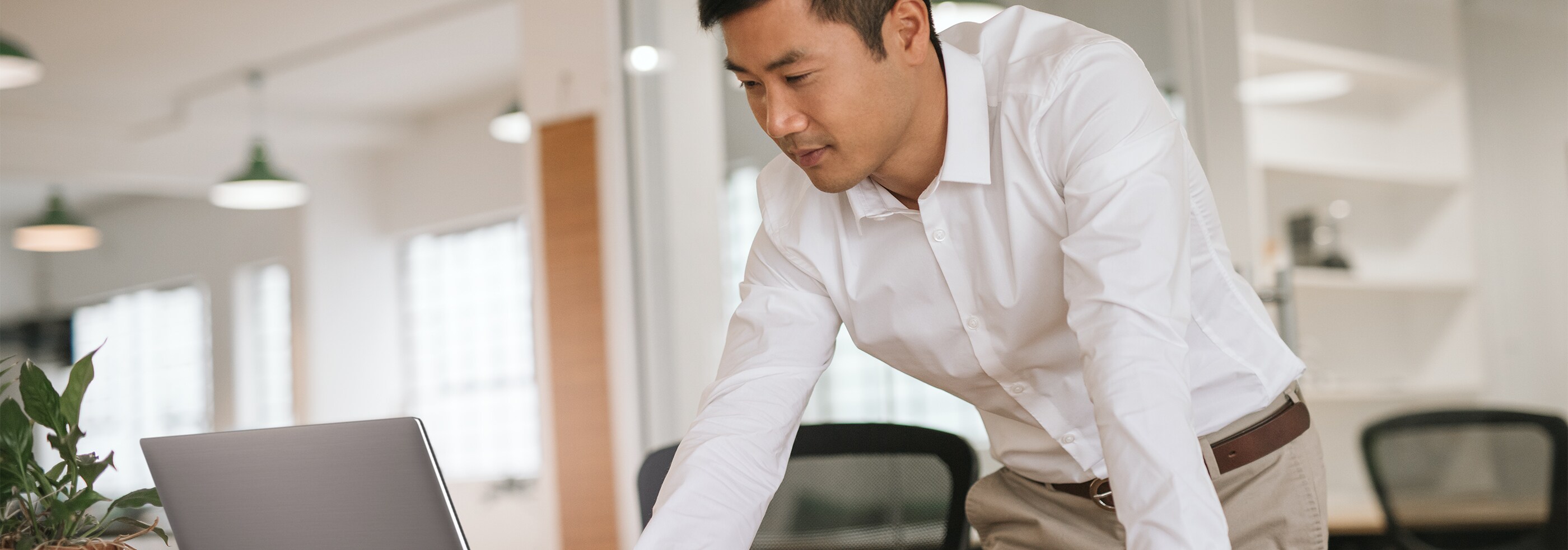 Un homme d’affaires concentré qui travaille sur son ordinateur portable dans un bureau moderne