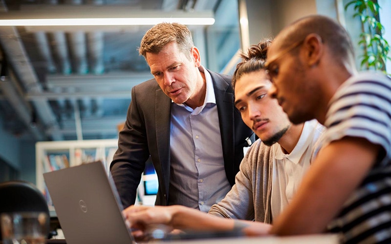 Male Workers Discussing with Manager Over a Laptop at a Desk in an Office