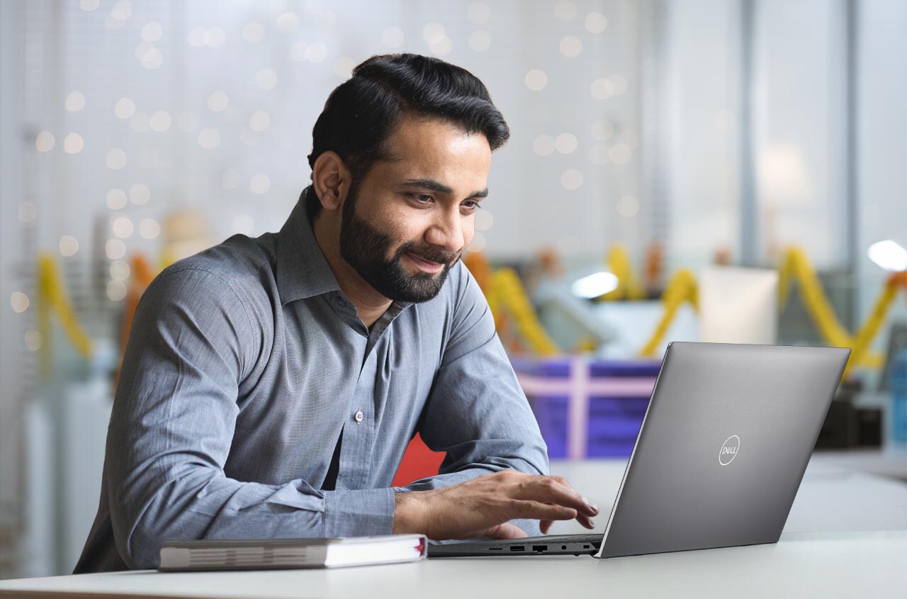 面带微笑的印度商人在办公室使用笔记本电脑工作