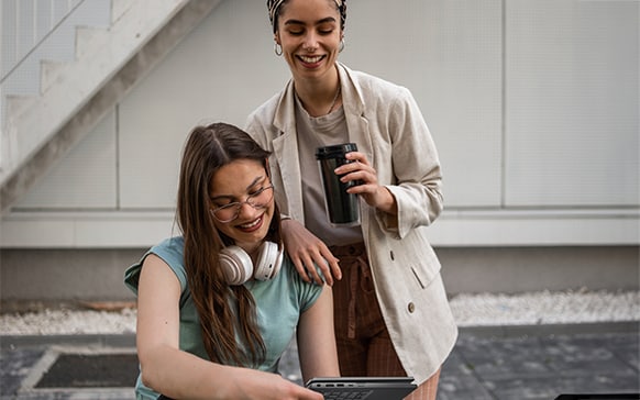A person holds up a tech device so another person can peer at the screen.