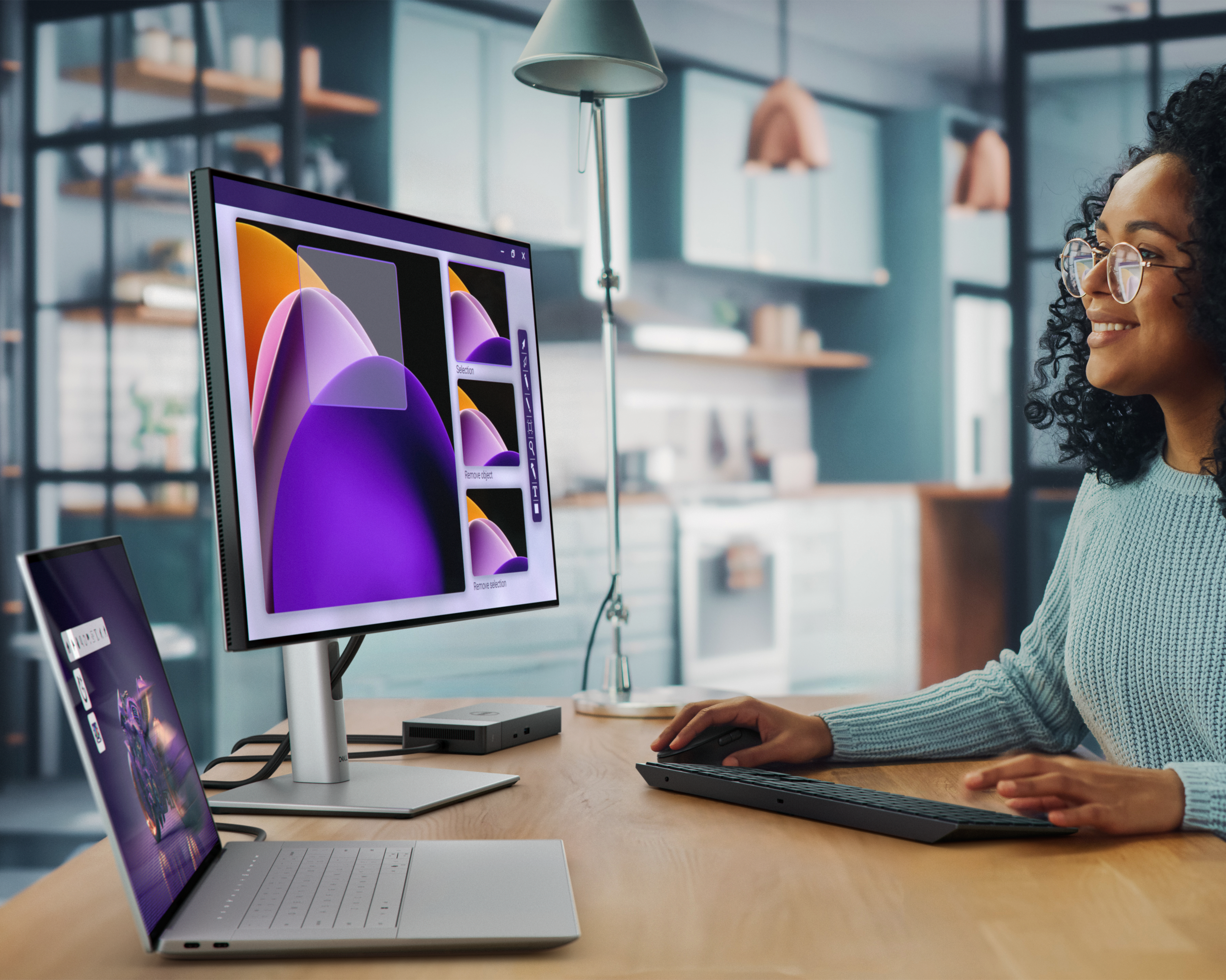 the image shows a woman working at her desk using a Dell Premium 16 laptop and an attached monitor.