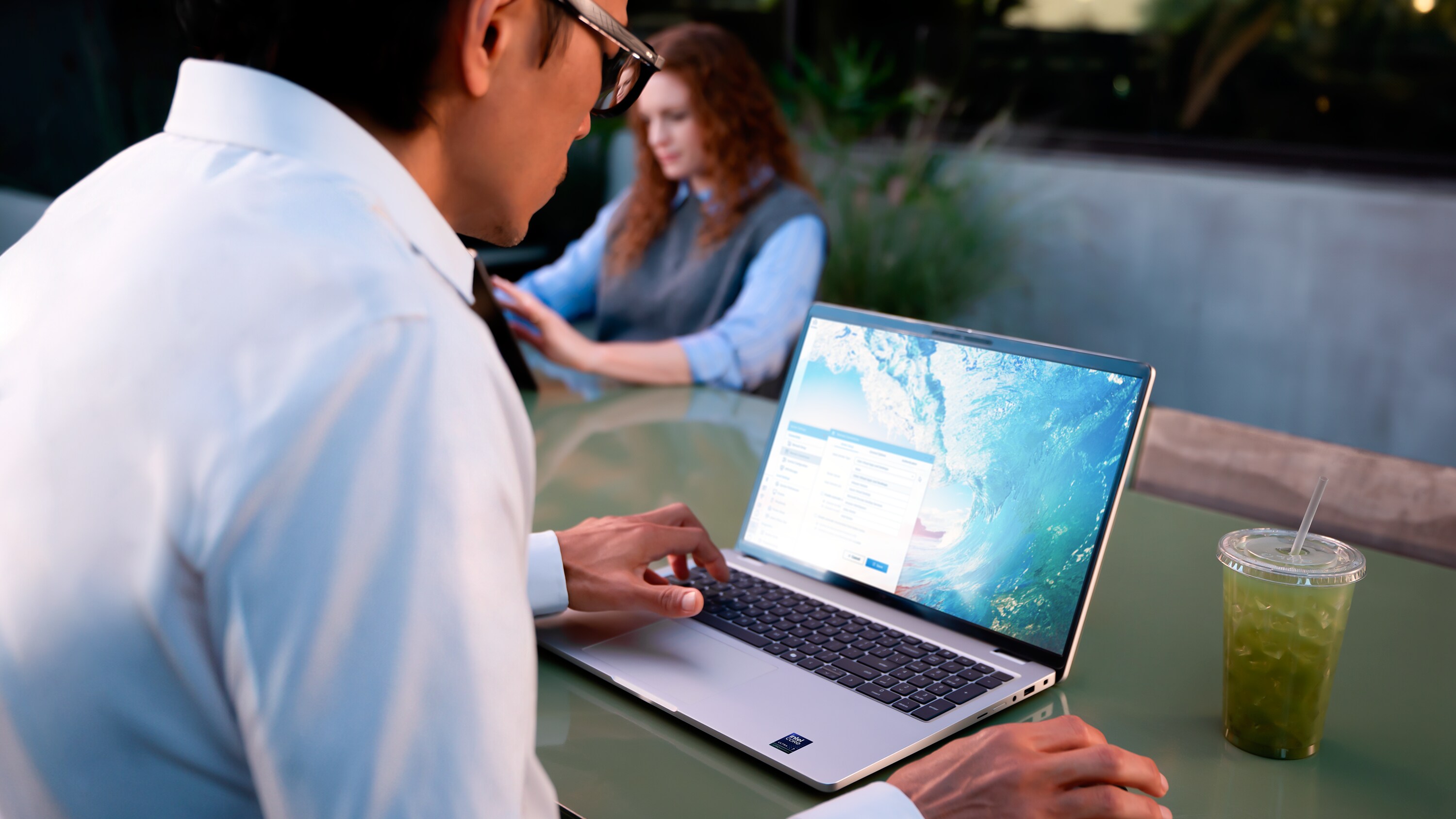 A photo of a person at a café table comfortably using a Dell Pro 16 Plus laptop thanks to it long battery life.