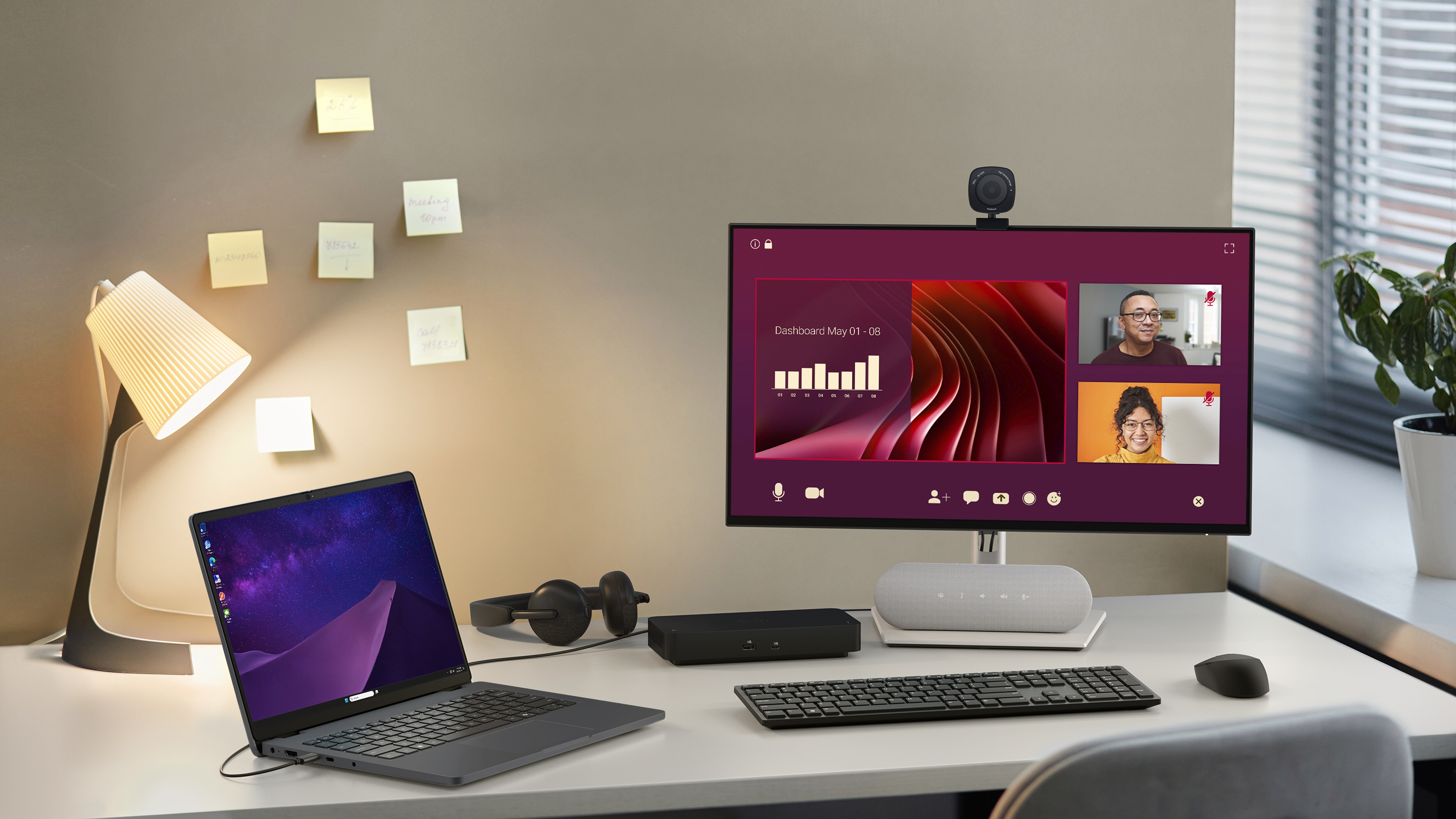 A neatly arranged desk with a Dell Pro 14 Laptop, a Dell desktop computer, webcam, wireless headphones and other accessories.