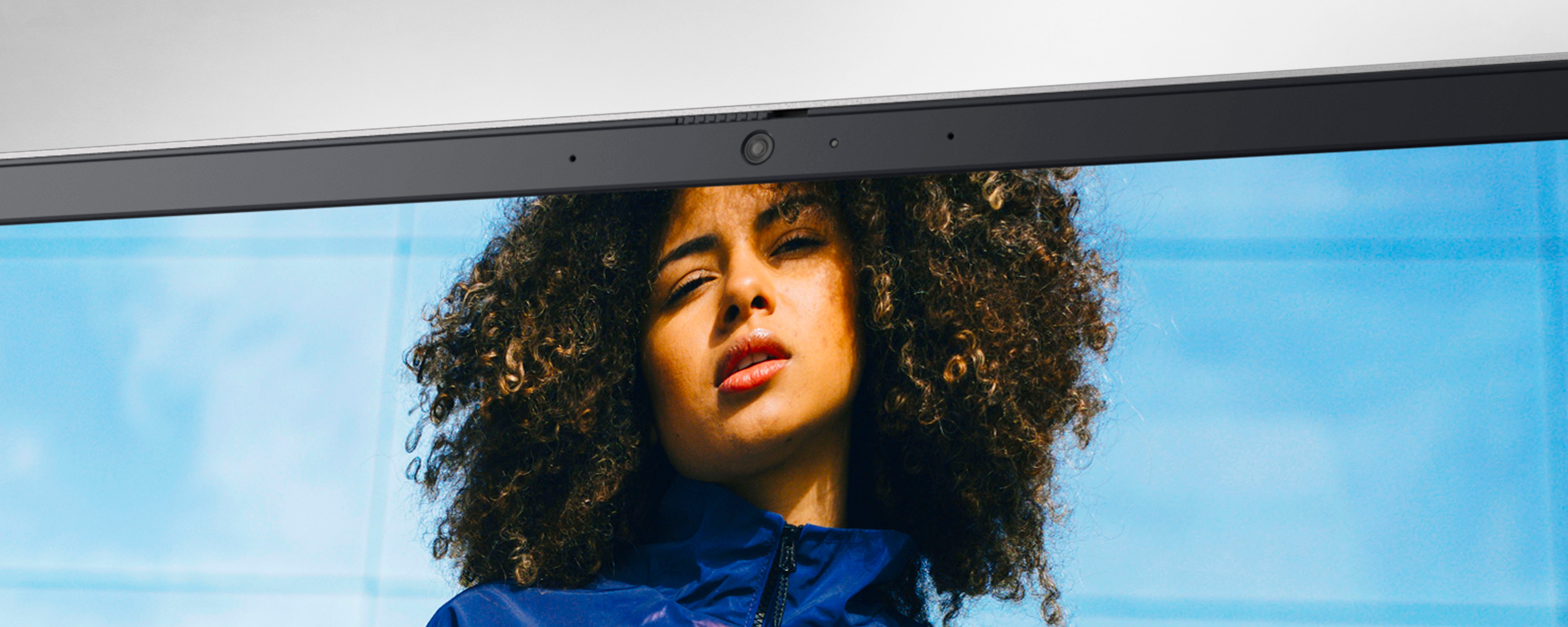 Bild eines Dell Inspiron-Laptopbildschirms von oben mit einer Frau, die eine dunkelblaue Jacke trägt und das Bild vor ihr anschaut.