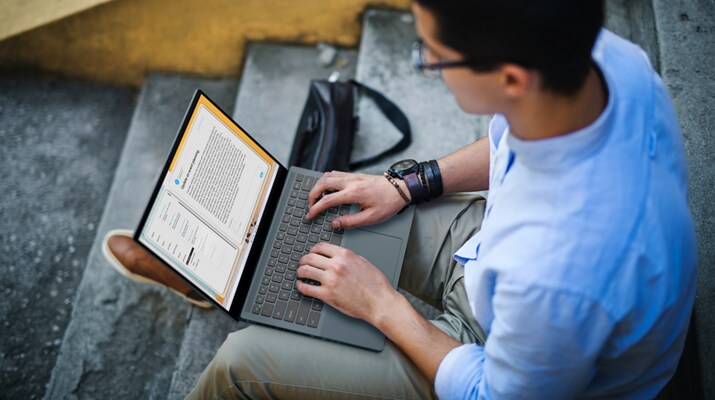 Image d’un homme assis avec un ordinateur portable Dell Inspiron 14 7420 sur les genoux, les mains sur le clavier.