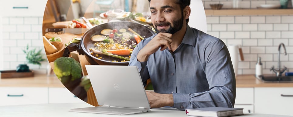 Man in a kitchen using a Dell Inspiron 14 7430 2-in-1 Laptop leaning against a table. 