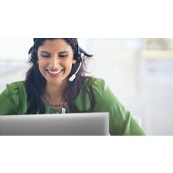 Smiley woman on a green shirt and a headset on her head using a Dell laptop.