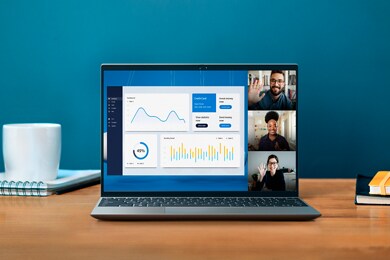 Picture of a Dell Vostro 13 5320 Laptop on a wood table with three different people on the screen.