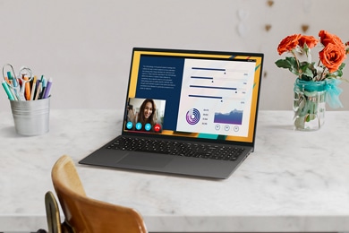 Picture of a Dell Vostro 16 5620 Laptop over a white marble table with a pen holder and a vase of flowers aside.