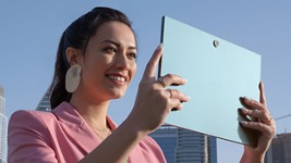 Picture of a woman wearing a pink blazer and typing on a Dell XPS 13 2-in-1 over a table.