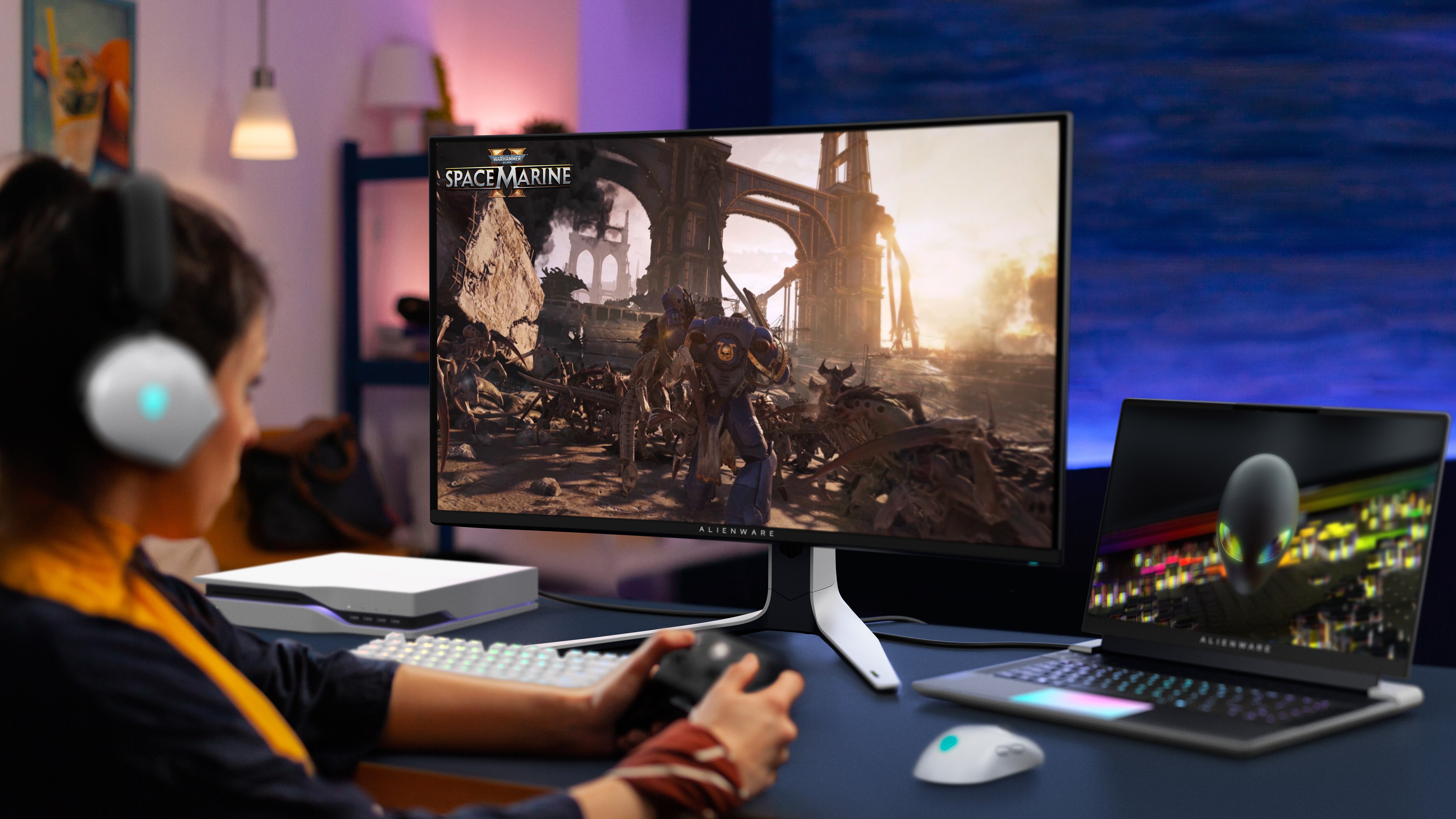 Woman playing Warhammer: The Last Stand on an Alienware product on her desk.