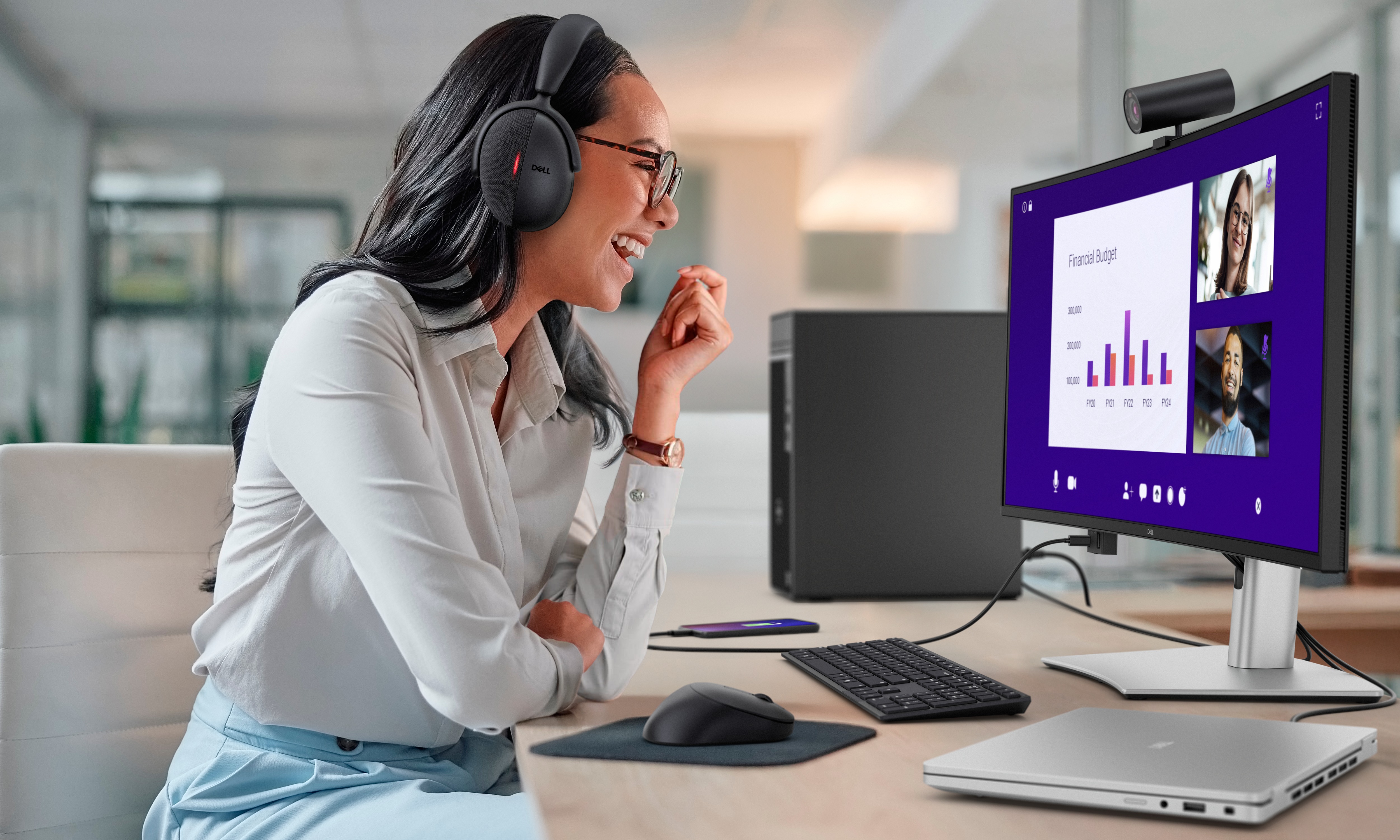 在 Dell Pro 34 Plus USB-C 集線器顯示器前戴著耳機工作的女性。