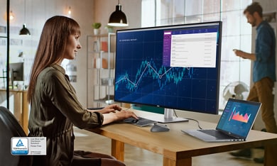 Woman sitting on an office chair typing on a keyboard and looking to a Dell UltraSharp U4323QE monitor.