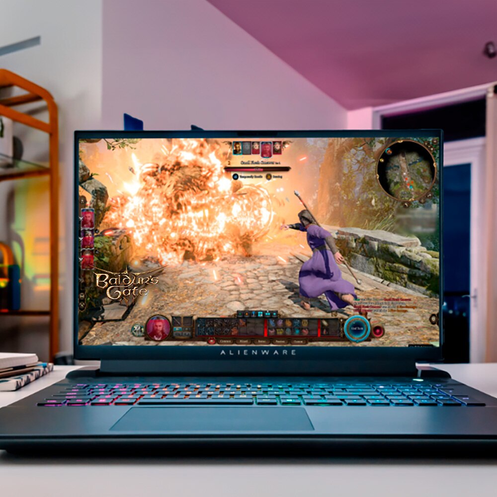Frontal view of an Alienware M18 R2 laptop sat on a table within a living room setting with the game Baldur's Gate visible on screen. 