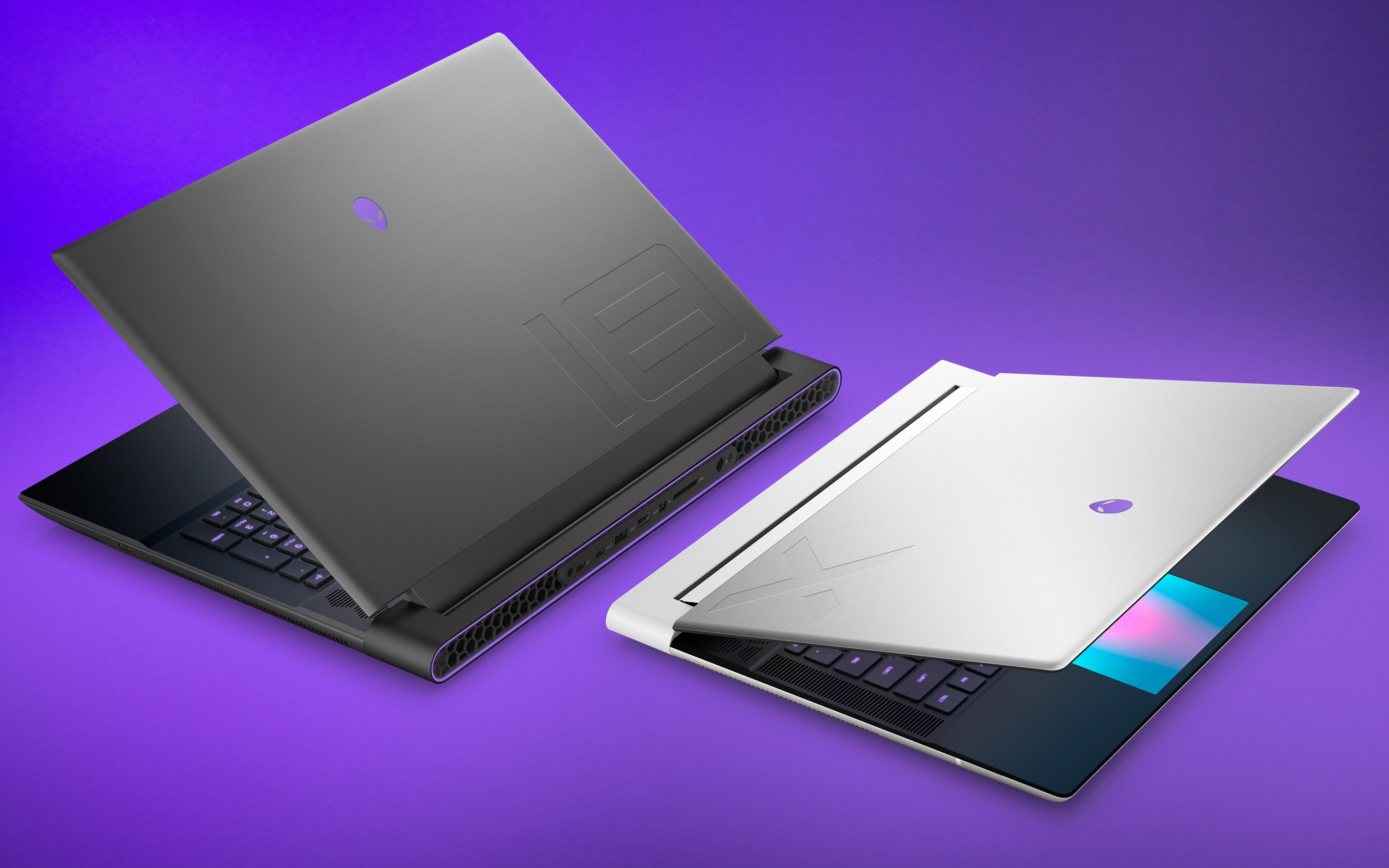 Two Alienware laptops are positioned back-to-back at 3-quarter angles, both slightly opened showcasing premium materials.