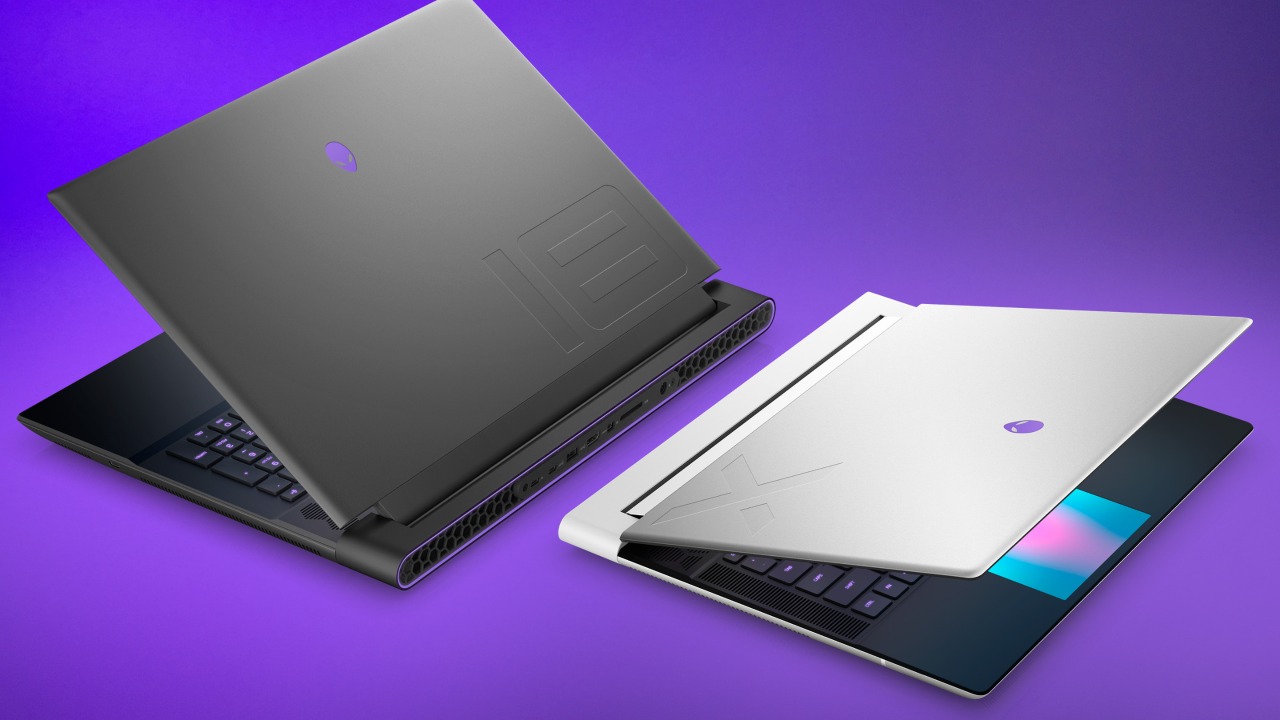 Two Alienware laptops are positioned back-to-back at 3-quarter angles, both slightly opened showcasing premium materials.