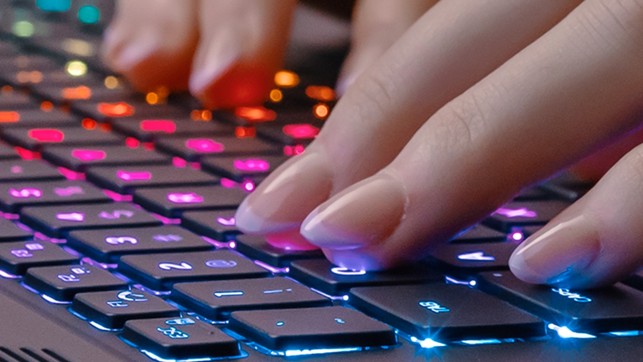 Close-up of fingers typing on a colorful, backlit keyboard. 