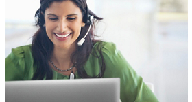 Người phụ nữ cười trên chiếc áo màu xanh lá cây và chiếc tai nghe trên đầu đang sử dụng máy tính xách tay Dell.