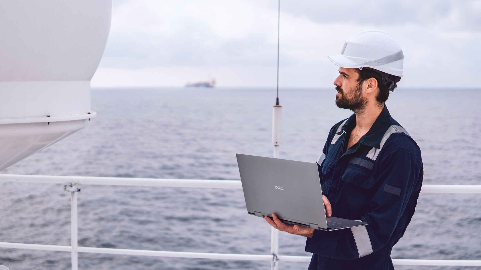 Technician on the Deck of a Ship Working on a Laptop