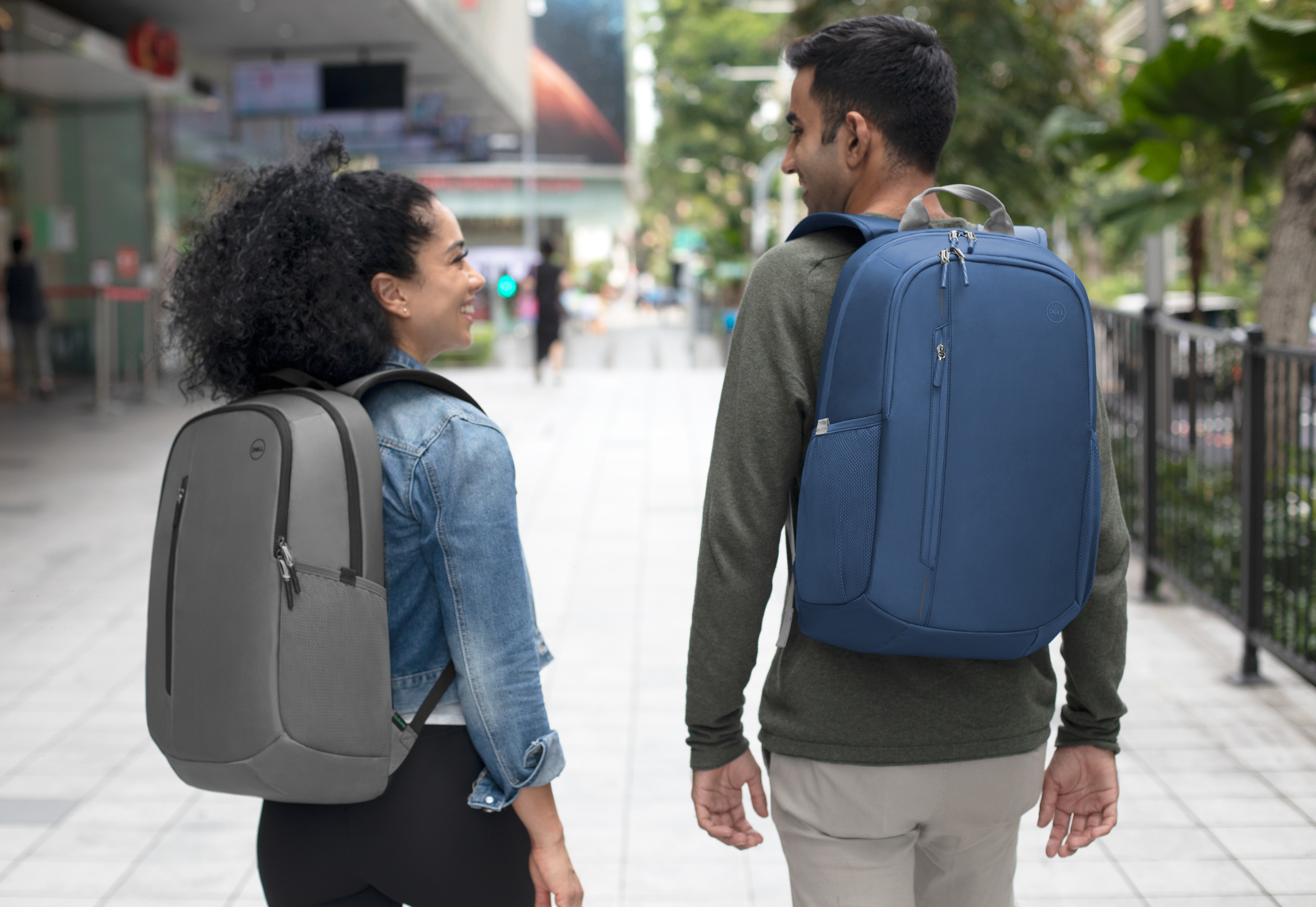 Picture of a man and woman side by side wearing Dell EcoLoop Urban Backpacks CP4523B.