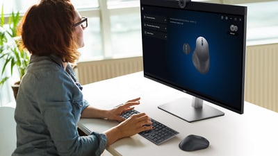 Woman using Dell products including a Dell MS900 Premier Rechargeable Mouse.